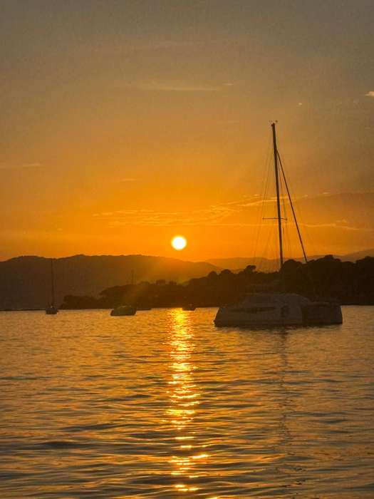 Sunset over the sea in front of a sailboat at anchor near Cap d'Antibes